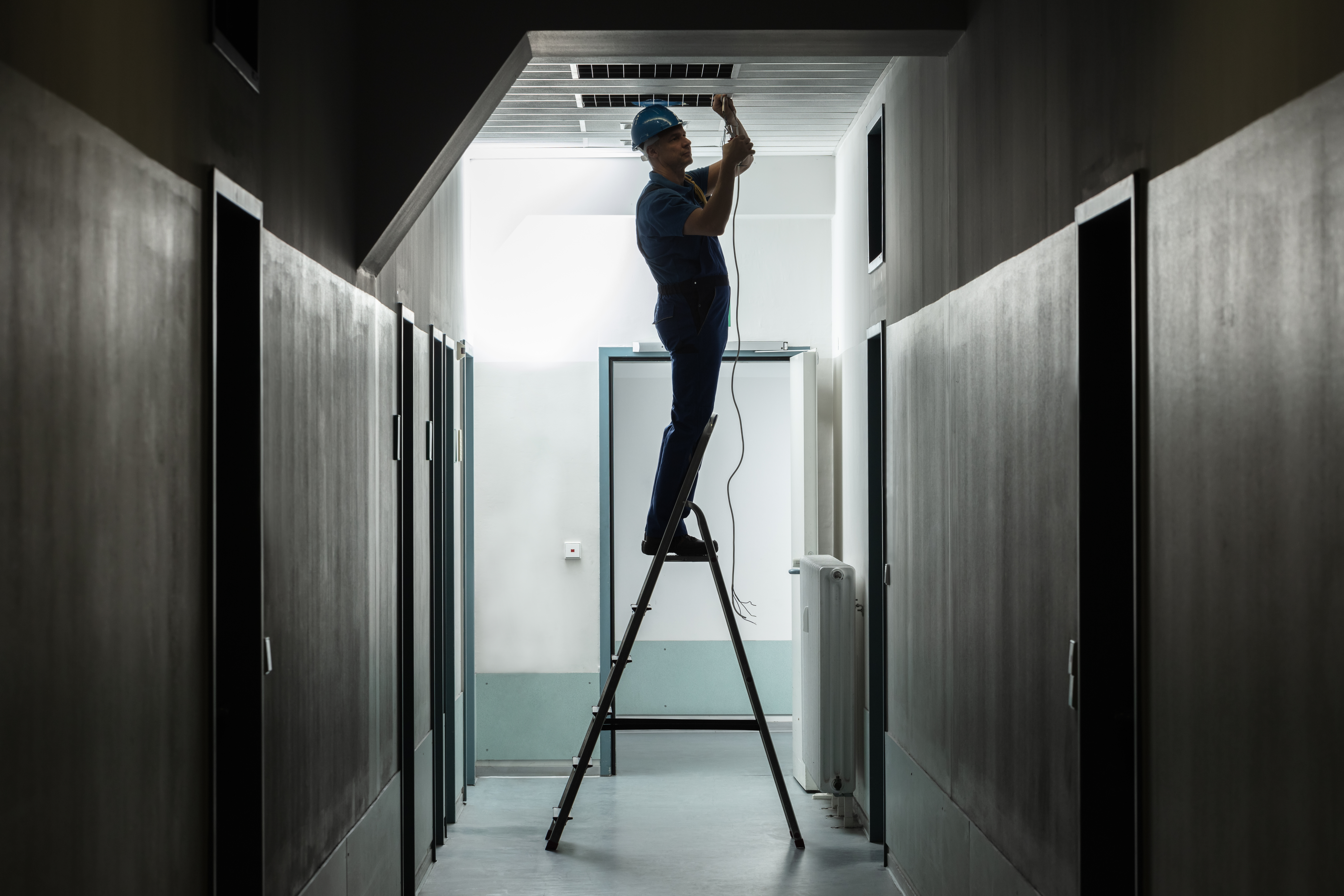 Silhouette,Of,A,Male,Electrician,On,Step,Ladder,Installing,Light